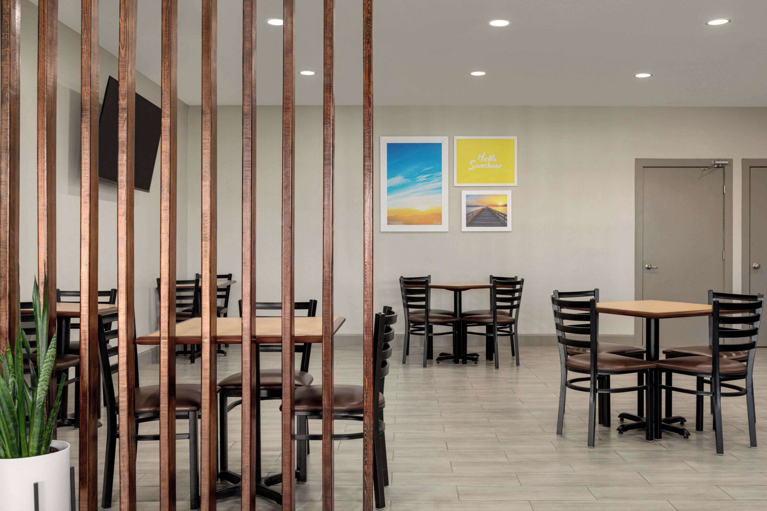 A modern dining area with wooden partitions, multiple tables and chairs, and framed pictures on the wall.