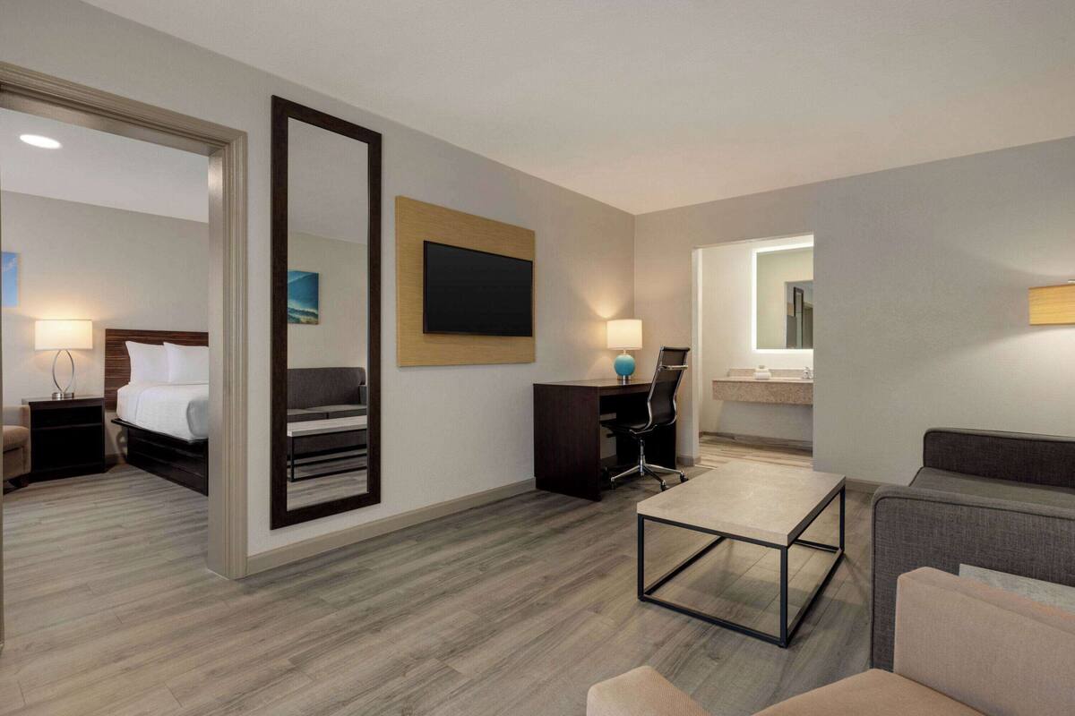 Une chambre d’hôtel comprenant un lit, un bureau, une chaise, un canapé, un miroir et une salle de bain.