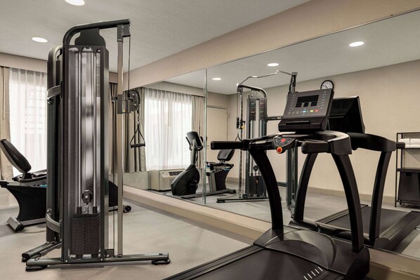 A gym with cardio equipment, a mirrored wall, and a treadmill.