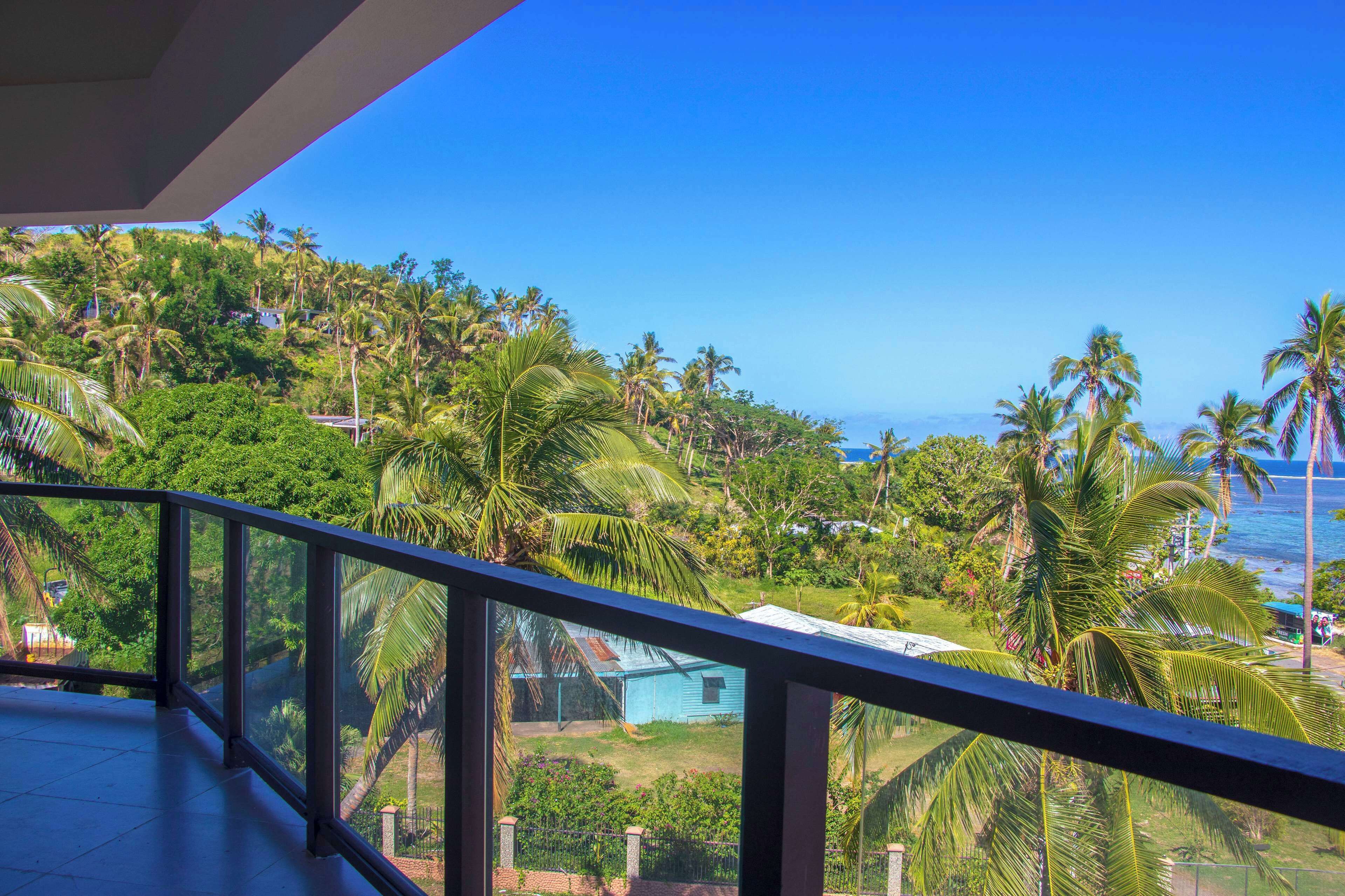 A balcony with a view of a lush green landscape and a clear blue sky.
