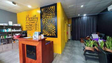 A reception area with a wooden desk, a yellow wall with a leaf design, and a black curtain in the background.