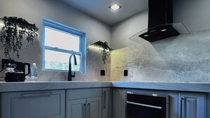 Une cuisine moderne avec des meubles gris, un four encastré et une fenêtre qui laisse entrer la lumière naturelle.
