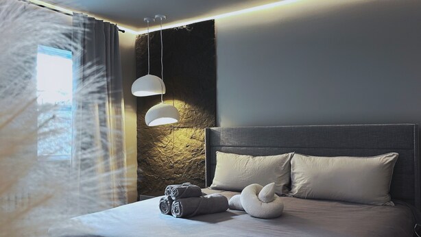 Une chambre à coucher moderne avec un grand lit, une tête de lit et un luminaire fixé au mur.