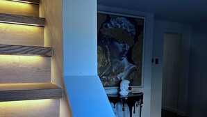 Un escalier avec des marches en bois, un mur blanc et un tableau représentant une femme.