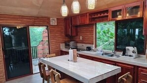 A kitchen with wooden cabinets, a marble countertop, and a large window.