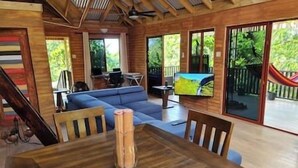 A wooden interior with a dining table, blue sofa, and a TV on a stand.