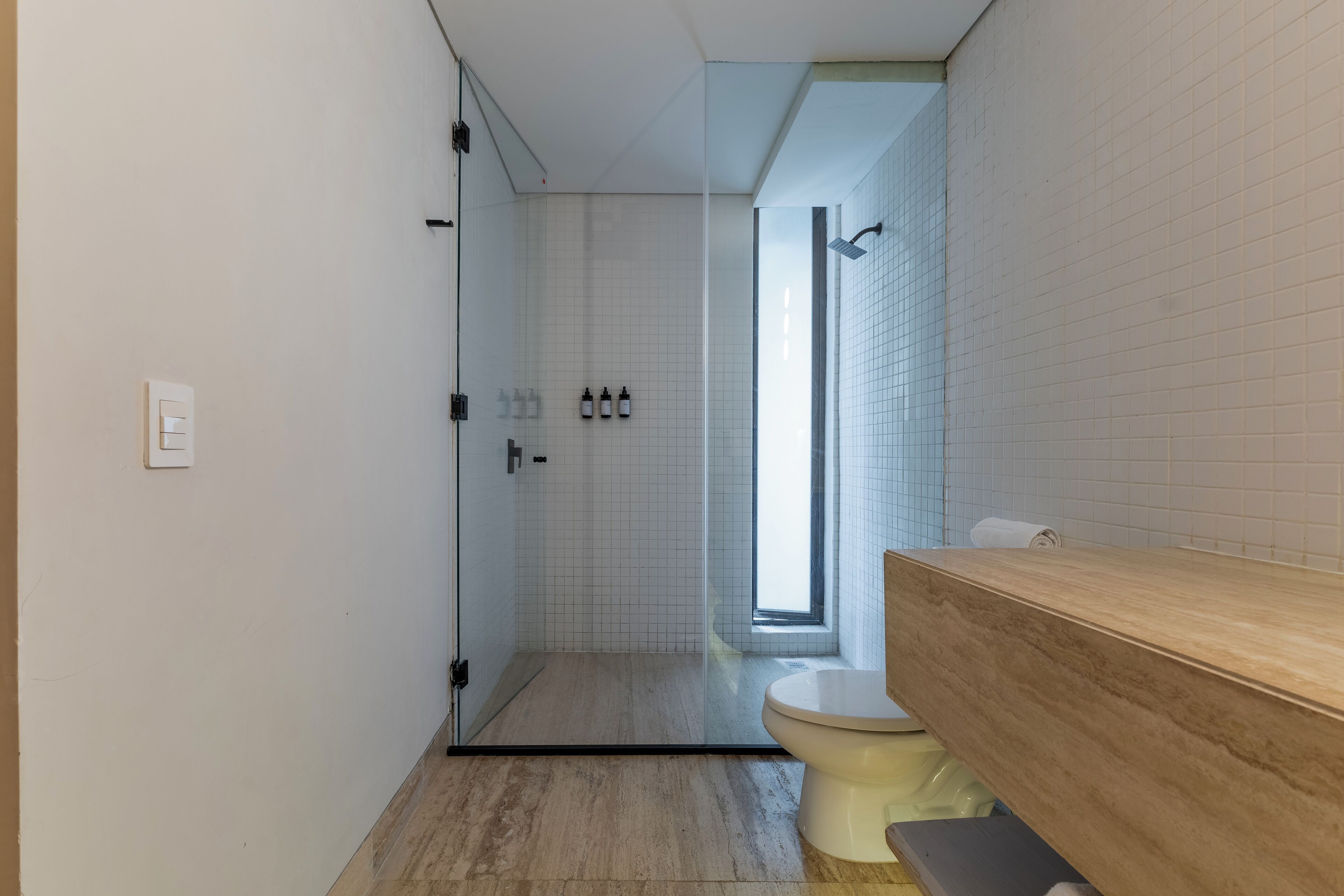 A modern bathroom with a glass shower enclosure, a toilet, and a wooden vanity.
