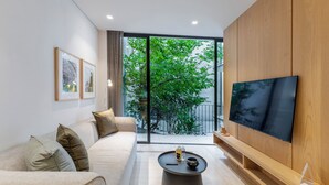 A modern living room with a sofa, coffee table, and a flat-screen TV mounted on a wooden wall.
