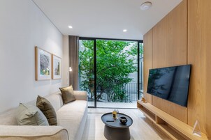Una sala de estar moderna con un sofá, una mesa de centro y un televisor de pantalla plana montado en una pared de madera.