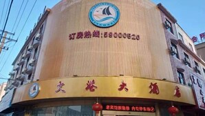 Un bâtiment à la façade circulaire, avec un logo en haut et une enseigne portant des caractères chinois.