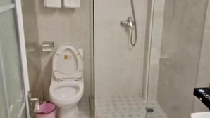 Une salle de bain comprenant des toilettes, une douche et un espace douche séparé par des parois en verre.