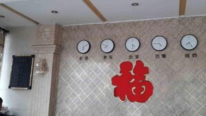 Un mur orné d’horloges et de caractères chinois, indiquant qu’il s’agit d’un hôtel ou d’un établissement similaire.