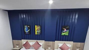 A hotel room with two beds, each with a wooden frame and a red bedspread. There are two nightstands with lamps, and a blue curtain with vertical stripes.