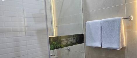 A modern bathroom with a glass-enclosed shower, a toilet, and a towel rack.