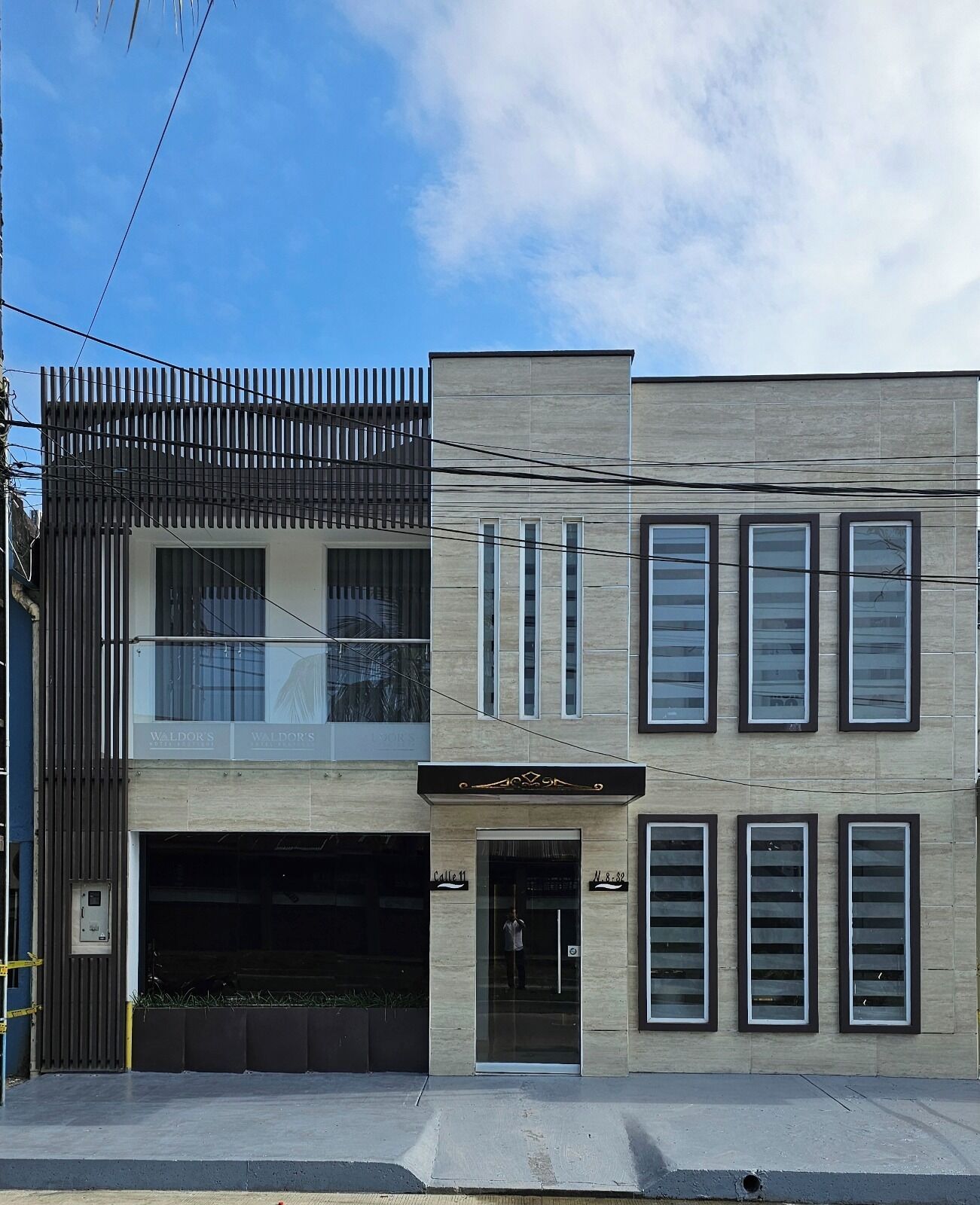 Un edificio de dos pisos con diseño moderno, que cuenta con un garaje en la planta baja y un balcón en el nivel superior.