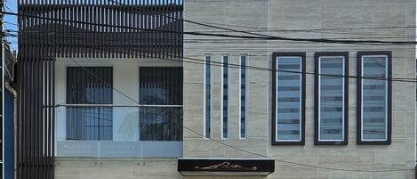 Un edificio de dos pisos con diseño moderno, que cuenta con un garaje en la planta baja y un balcón en el nivel superior.