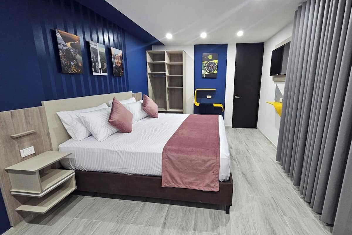 Une chambre à coucher moderne, équipée d’un lit, de tables de chevet, d’une armoire et d’un téléviseur.