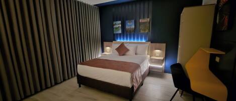 A modern hotel room with a large bed, bedside tables, a desk, and a chair.