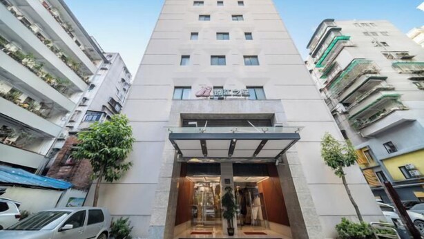 Un hôtel moderne doté d’une entrée centrale, de plusieurs étages et offrant une vue sur un ciel dégagé.
