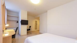 Une chambre d’hôtel comprenant un lit, un bureau, une chaise, une télévision et une salle de bain.