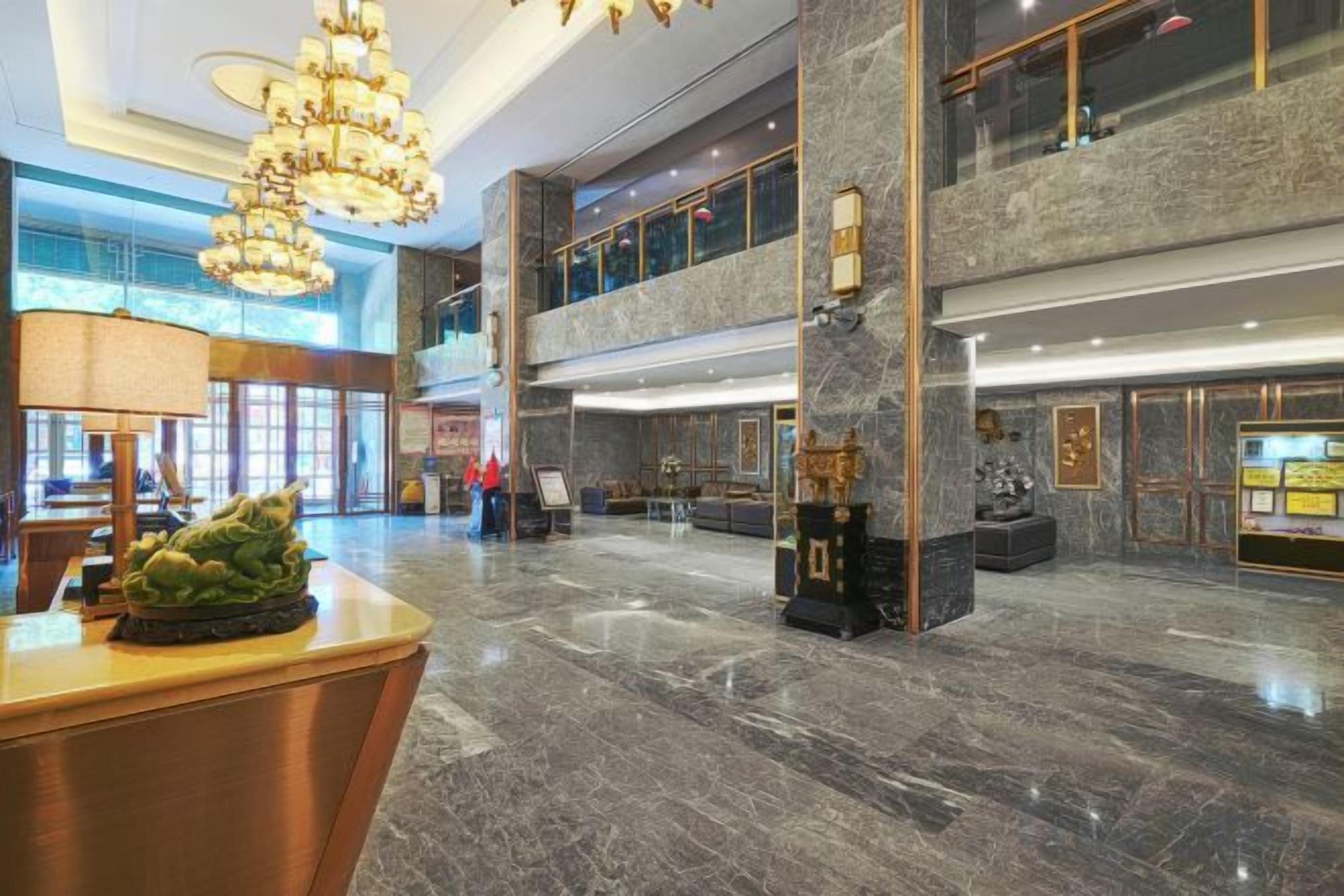 A spacious lobby with a reception desk, a chandelier, and a marble floor.