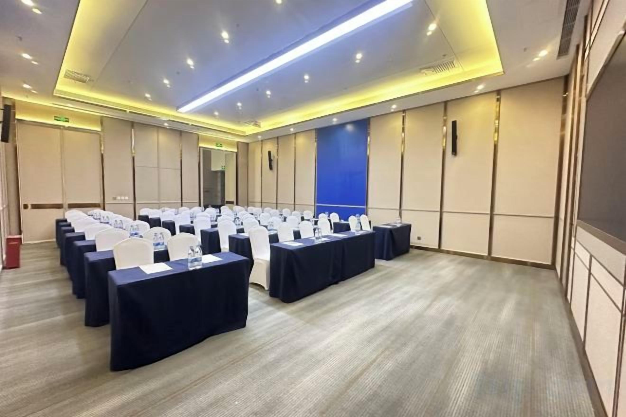 A conference room with rows of tables and chairs, equipped with nameplates and water bottles.