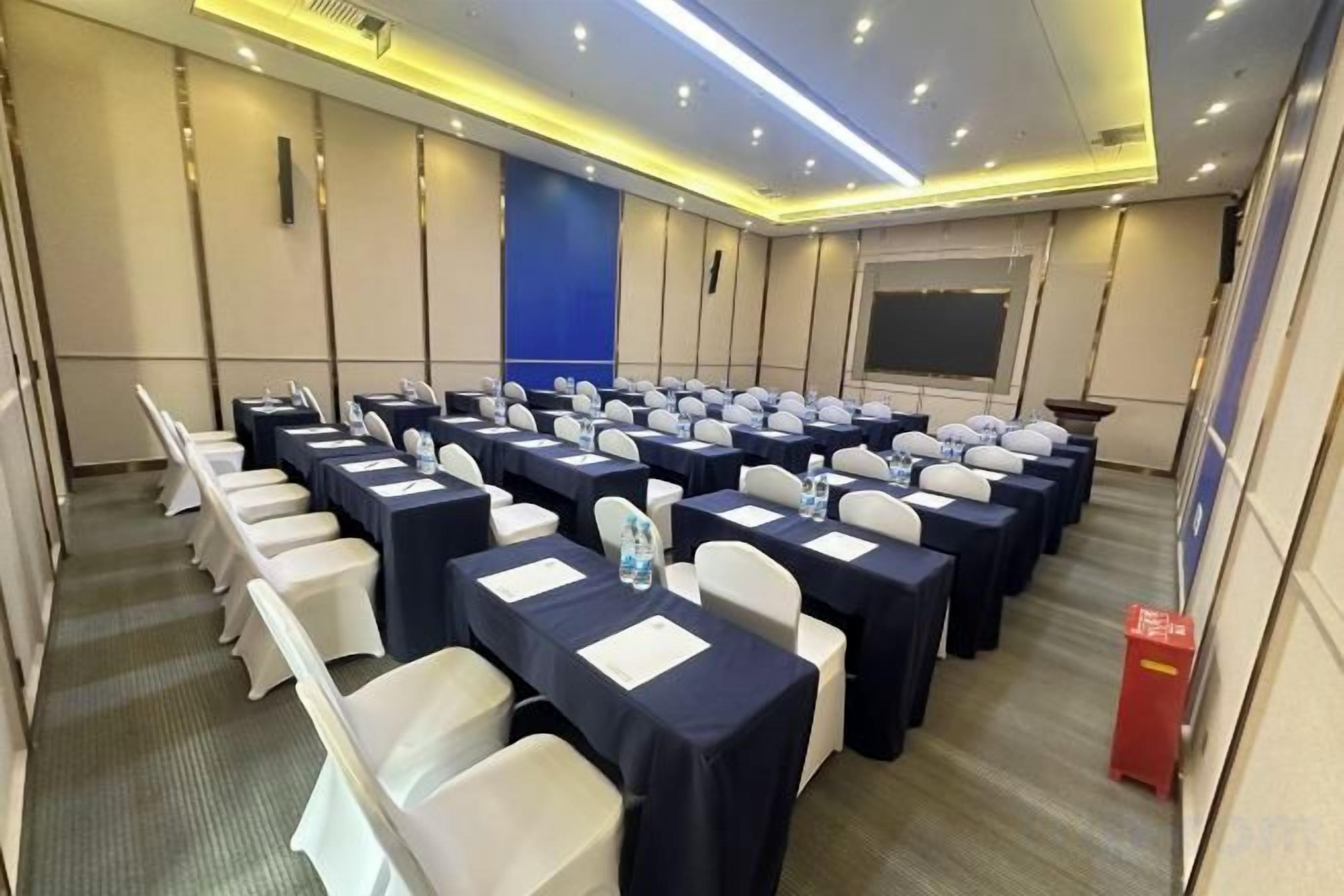 A conference room with rows of tables and chairs, equipped with nameplates and water bottles.