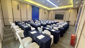 A conference room with rows of tables and chairs, equipped with nameplates and water bottles.