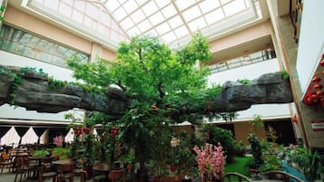 An indoor atrium with a central tree, seating areas, and a high ceiling with skylights.