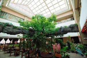 Un atrio interior con un árbol central, zonas de estar y un techo alto con tragaluces.