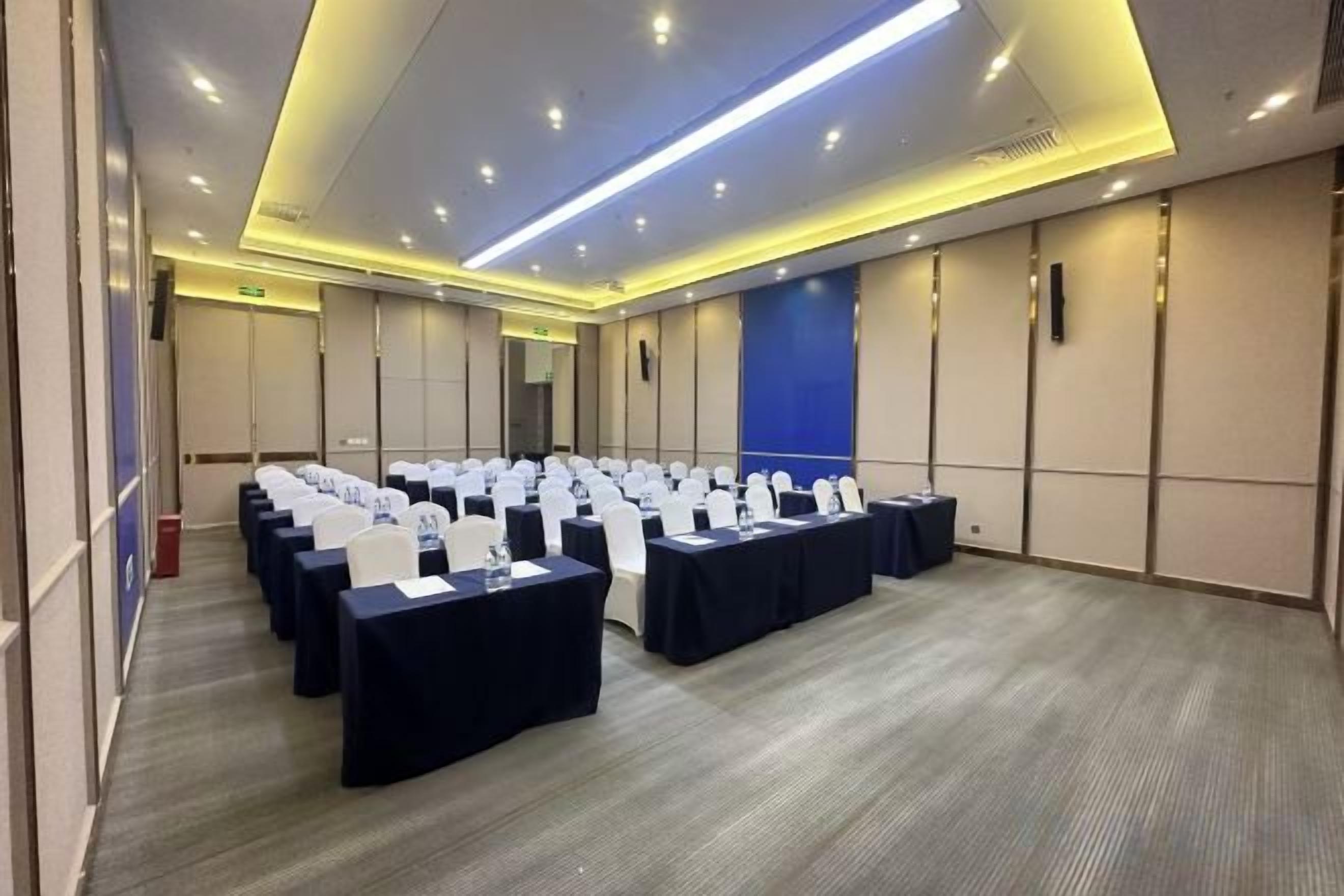 A conference room with rows of tables and chairs, equipped with nameplates and water bottles.