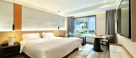A modern hotel room with a large bed, bedside tables, a desk, and a TV.