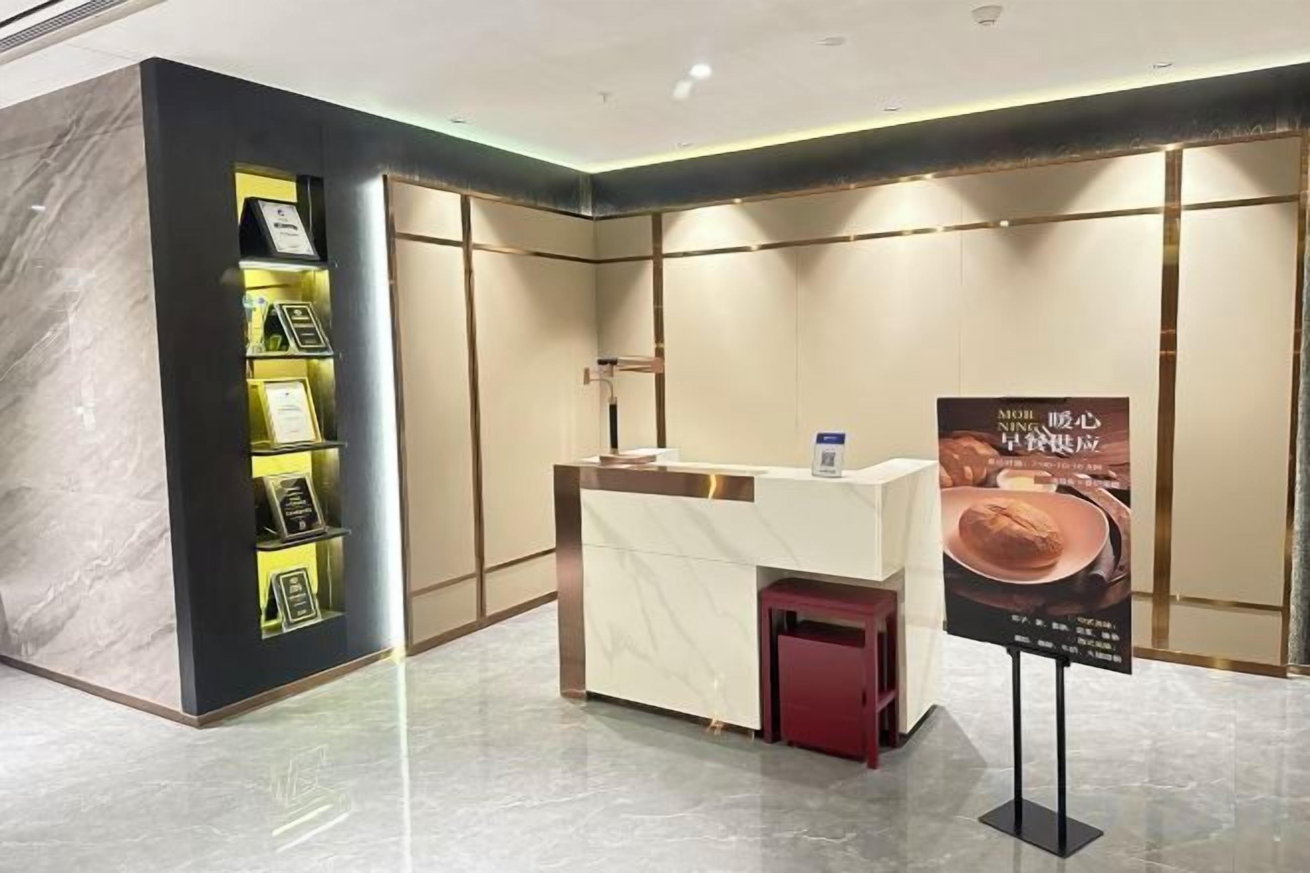 A reception area with a marble reception desk, a small red trash bin, and a wall-mounted information stand.
