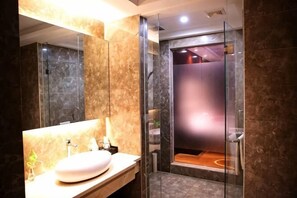 Egy modern fürőszoba márvány mosdóval, üveg zuhanykabinnal és jól látható WC-vel.