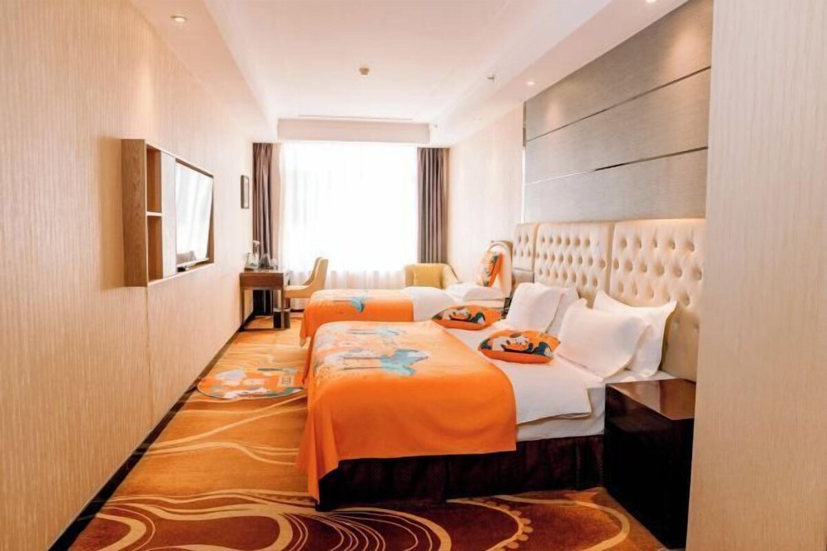Quarto de hotel com duas camas, uma janela grande, TV e minibar.