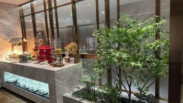 A reception area with a marble counter, a coffee machine, a plant, and a glass display case.