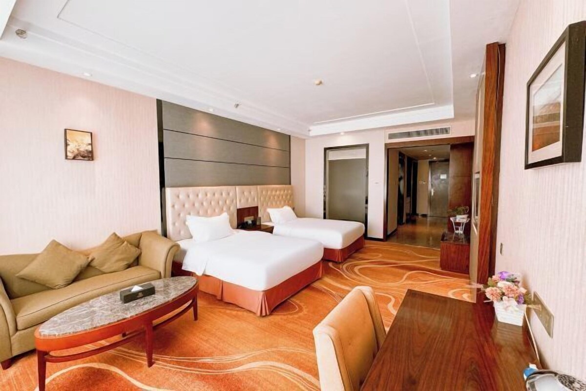 Quarto de hotel com duas camas, um sofá, uma mesa de jantar e uma pequena mesa de centro.