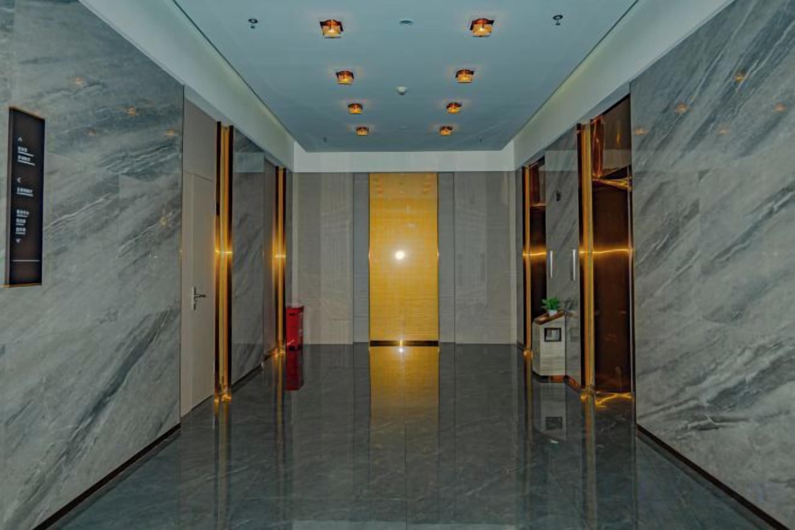 Un hall d’hôtel moderne avec un sol en marbre, un comptoir d’accueil et un luminaire au plafond diffusant une lumière vive.