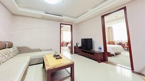 Une chambre d’hôtel avec un canapé, une petite table, une télévision et un miroir qui reflète la pièce.