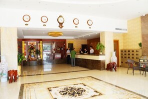 A hotel lobby with a reception desk, a clock, and a patterned carpet. - E·E Business Hotel (Guangzhou)