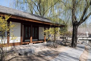 A traditional Japanese-style building with a tiled roof and wooden beams, surrounded by trees and a stone pathway. - Eastern Garden Hotel (Beijing)