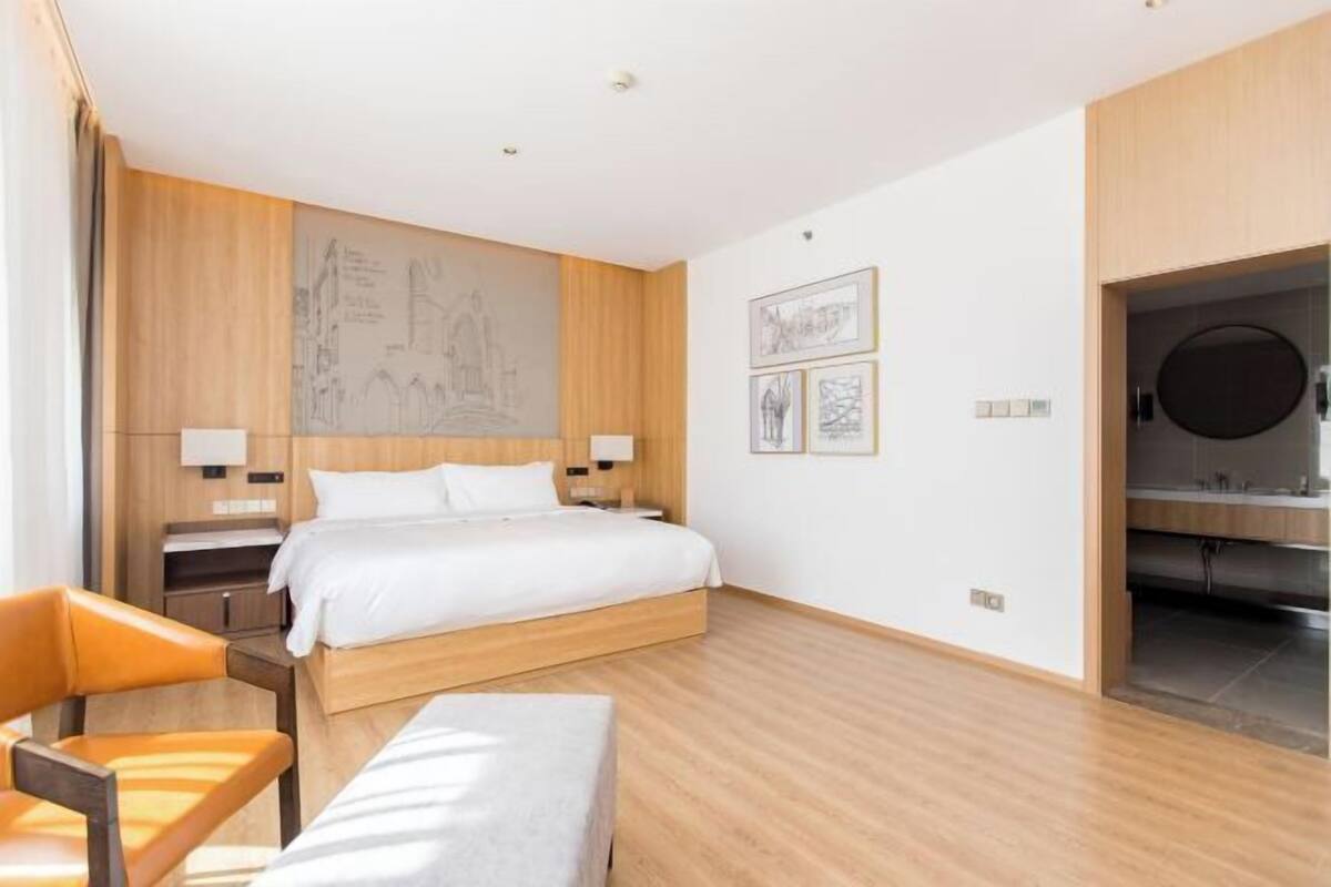 Une chambre d’hôtel moderne avec un grand lit, des panneaux de bois, un bureau et une chaise.