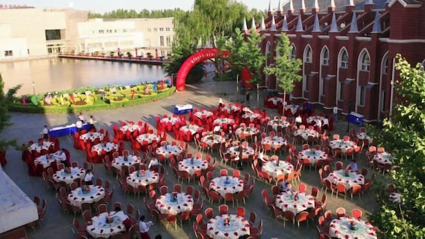 An outdoor dining area with numerous round tables and chairs, set up in a courtyard with a large building in the background. - Eastern Garden Hotel (Beijing)