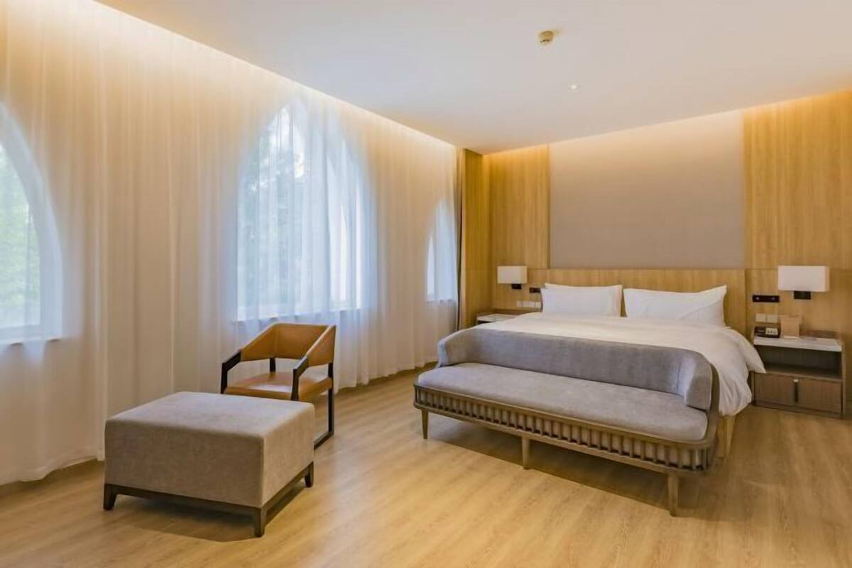 Une chambre d’hôtel moderne avec un grand lit, un petit canapé, une chaise et une table de chevet.