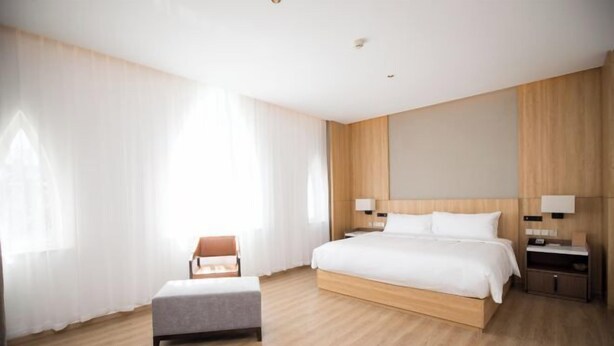 Ein modernes Hotelzimmer mit einem großen Bett, einem Nachttisch, einem Sessel und einem Beistelltisch.