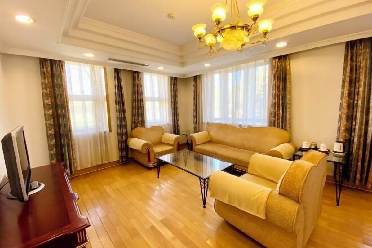 Un salon spacieux avec un grand canapé, une table basse et un téléviseur posé sur un meuble en bois.