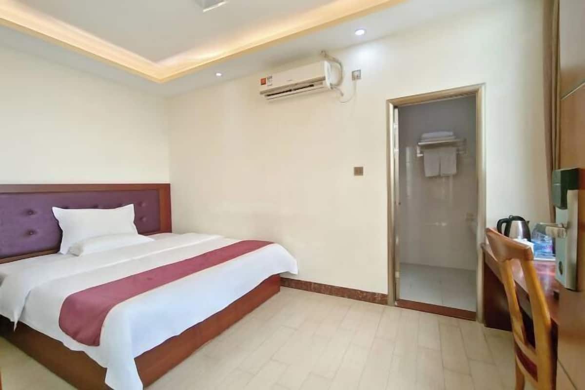 Een hotelkamer met een bed, een douche en een klein tafeltje met een waterkoker.