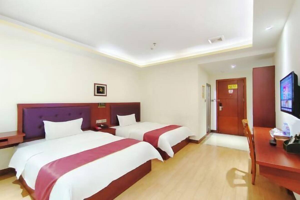 Een hotelkamer met twee bedden, een bureau, een stoel en een televisie.