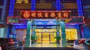 Ingresso di un hotel con insegna al neon, vetrate e piante in vaso.