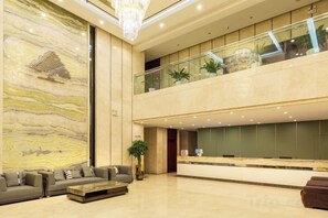 A spacious lobby with a reception desk, seating area, and a large marble wall. - GreenTree Inn (Nantong Third Factory Wangjiang North Road) (Nantong)